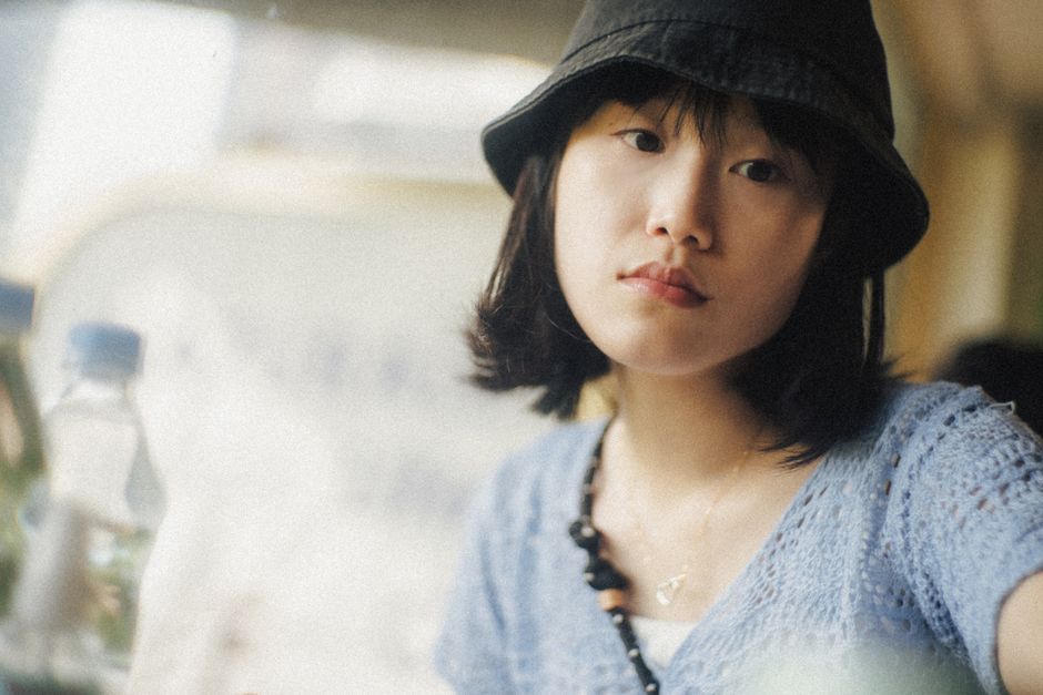 Casual portrait of a young woman in a Hong Kong café wearing a hat.