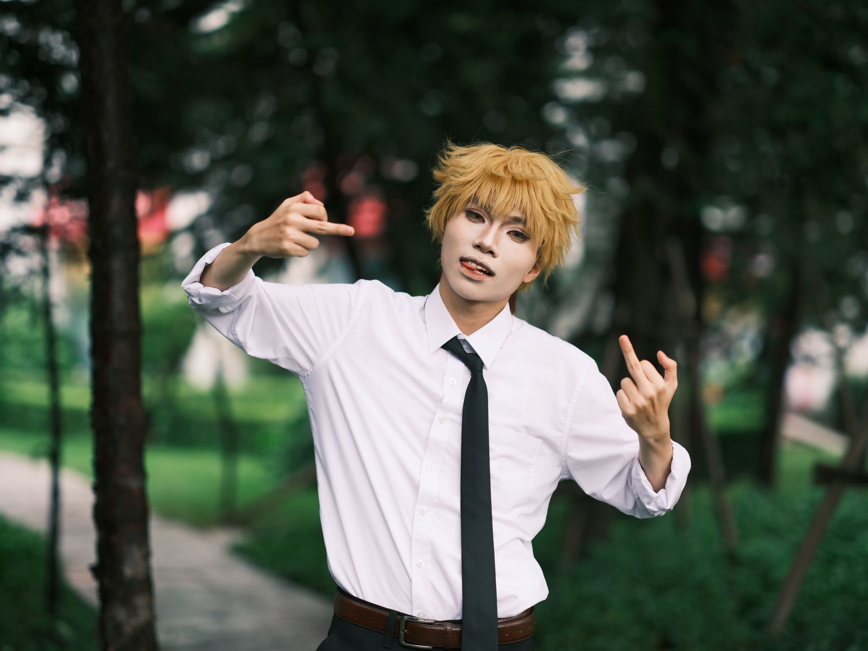 A cosplayer energetically poses in a park, showcasing expressive cosplay fashion.