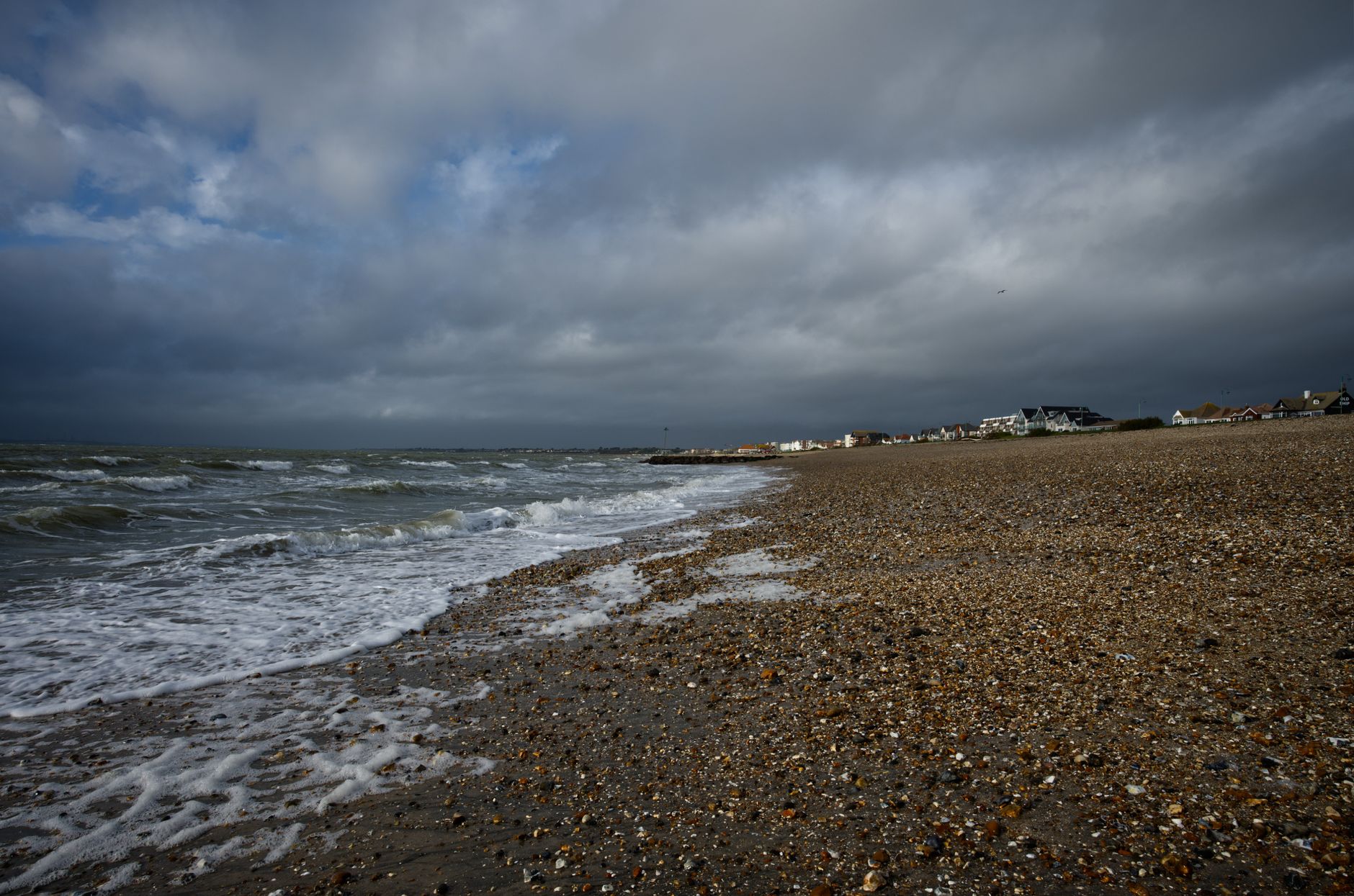 Moody beach scene at Lee-on-the-Solent, England, with stormy skies and waves crashing ashore.