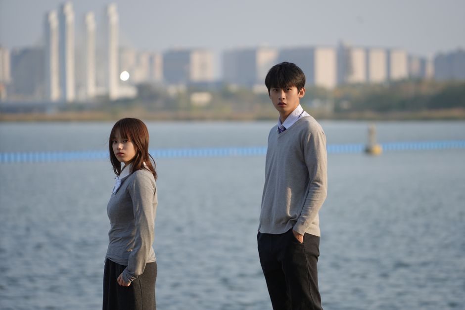 Young couple standing by a waterfront with cityscape in Zhengzhou, China.
