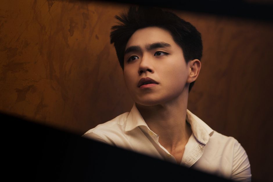 A dramatic portrait of a young man in a contemplative pose indoors.