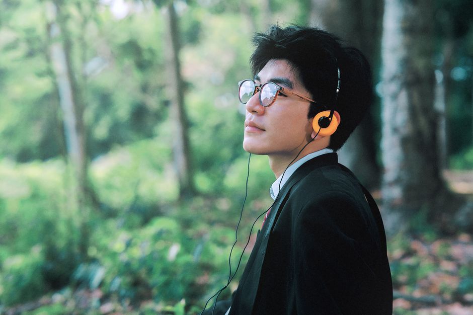 Man listening to music outdoors, enjoying a peaceful moment in lush greenery.