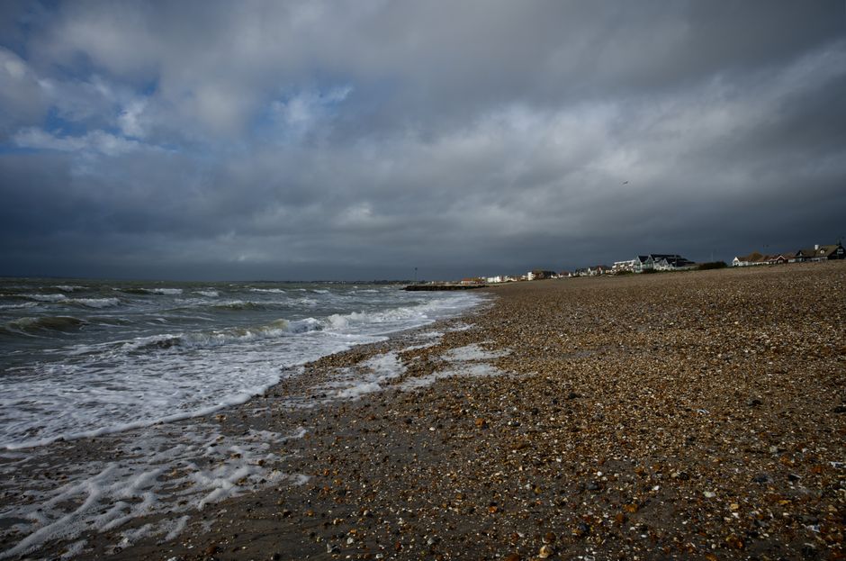 Moody beach scene at Lee-on-the-Solent, England, with stormy skies and waves crashing ashore.