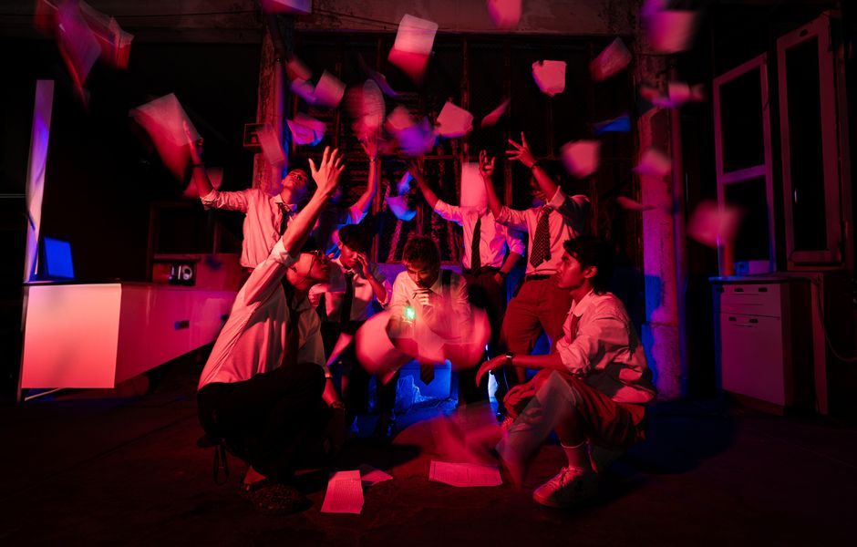 Group of colleagues celebrating at night with papers flying in dramatic red light.